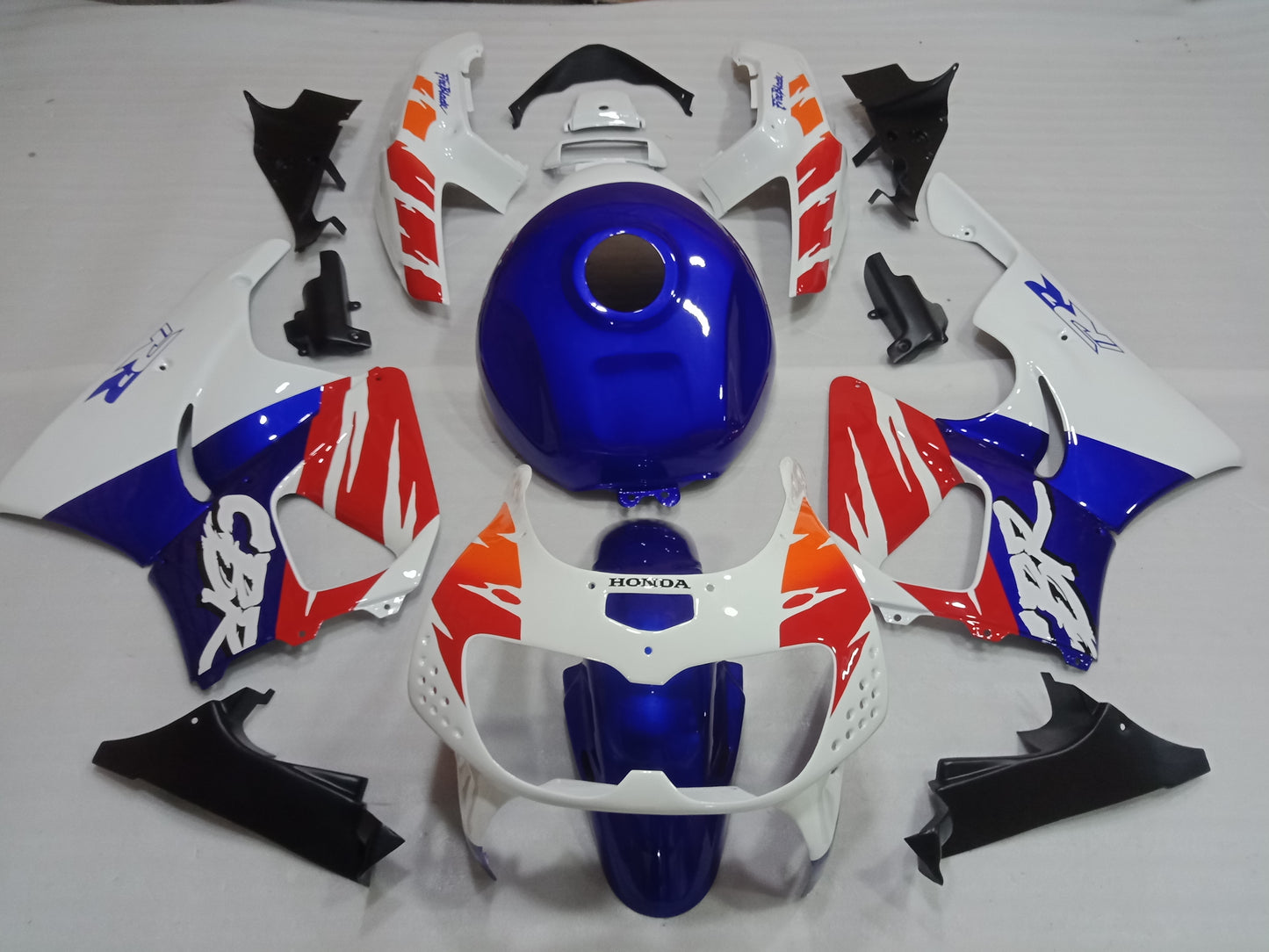 A set of motorcycle fairings for Honda CBR900RR in blue, white, red, and black colors, including pieces for the body, tank cover, and windscreen.