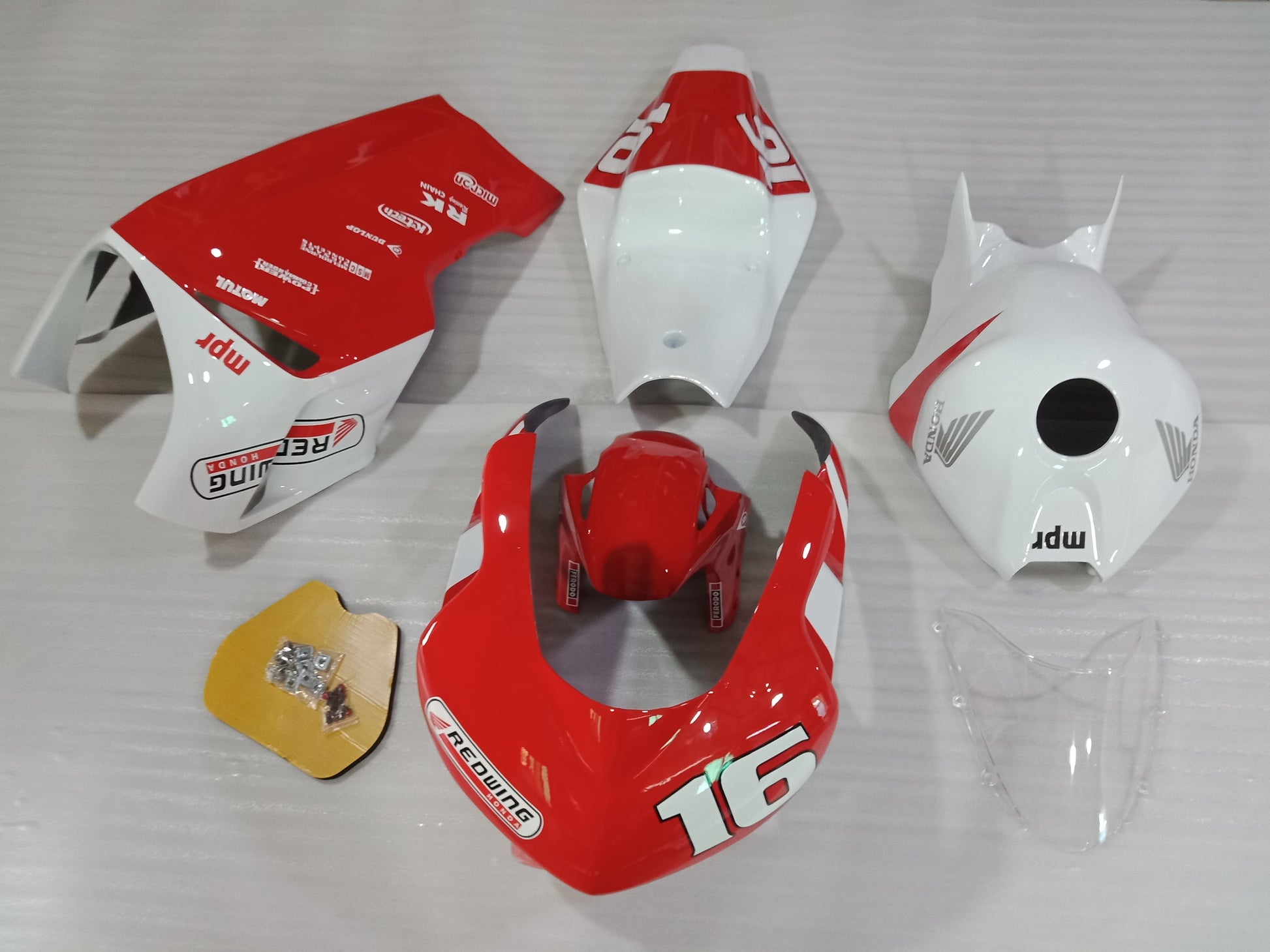 A set of red and white fiberglass motorcycle fairings for a HONDA CBR1000RR, including pieces for the front fender, upper and lower body, and race tail.