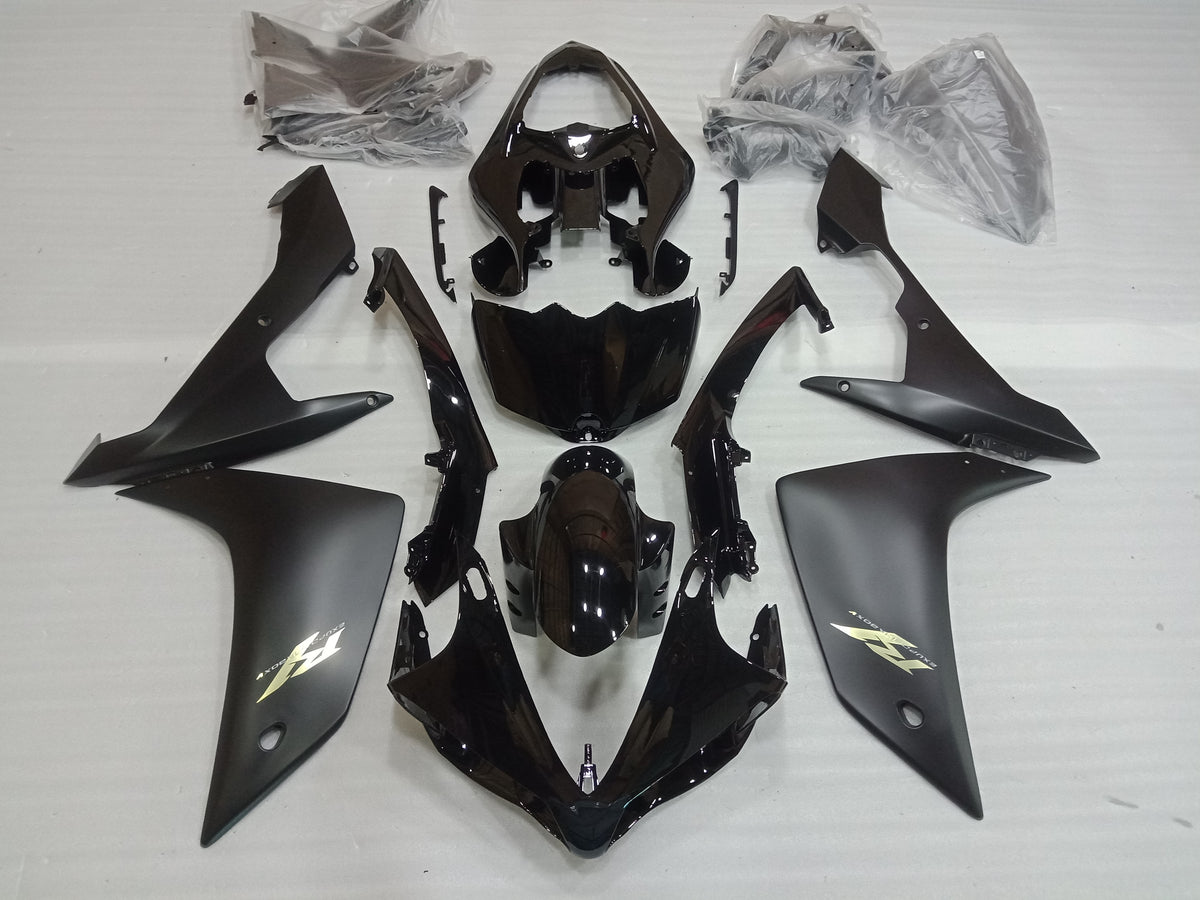 A set of black motorcycle fairings laid out on a white surface, including various panels and a windscreen.