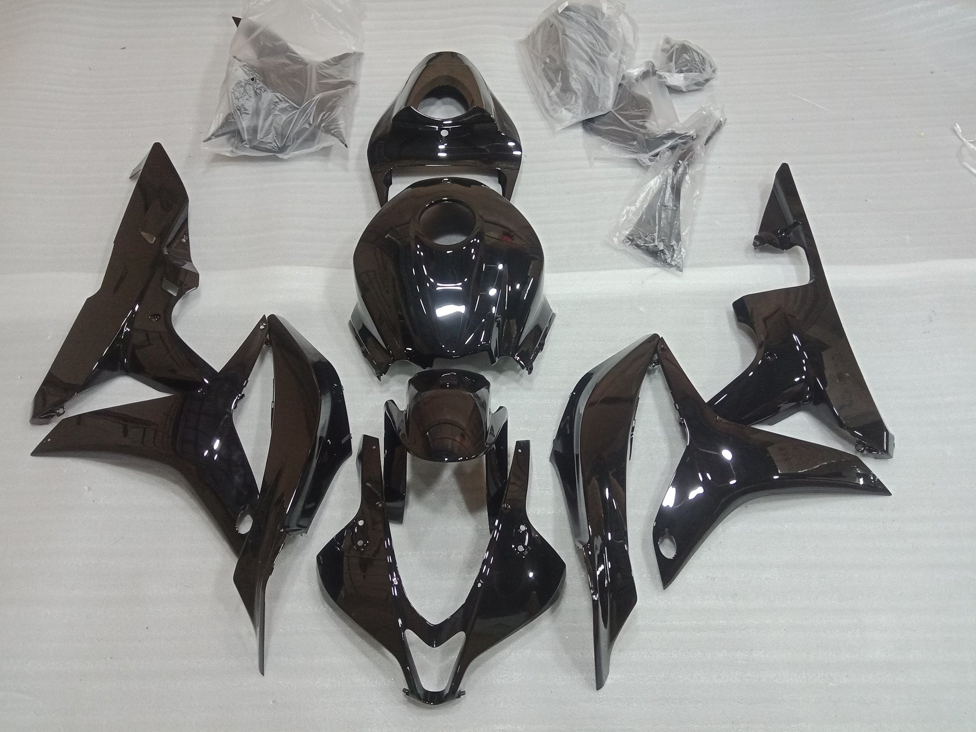 A set of gloss black motorcycle fairings laid out on a white surface, including various panels and bolts, for a Honda CBR600RR.