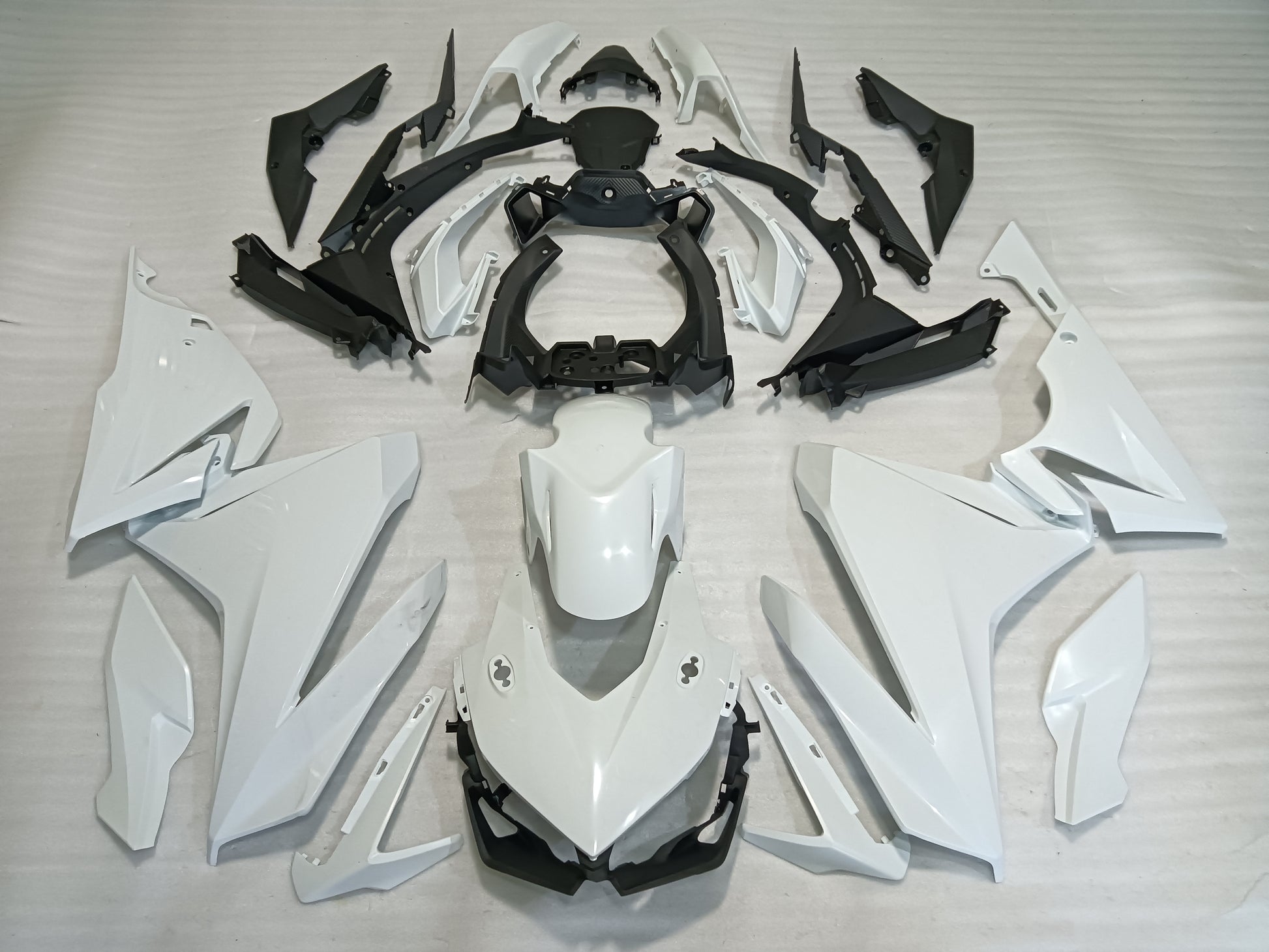 A set of unpainted fairing panels for Honda CBR500R motorcycle, laid out on a white surface, including various pre-drilled precision OEM perfect fitment panels in black, white, and gray.