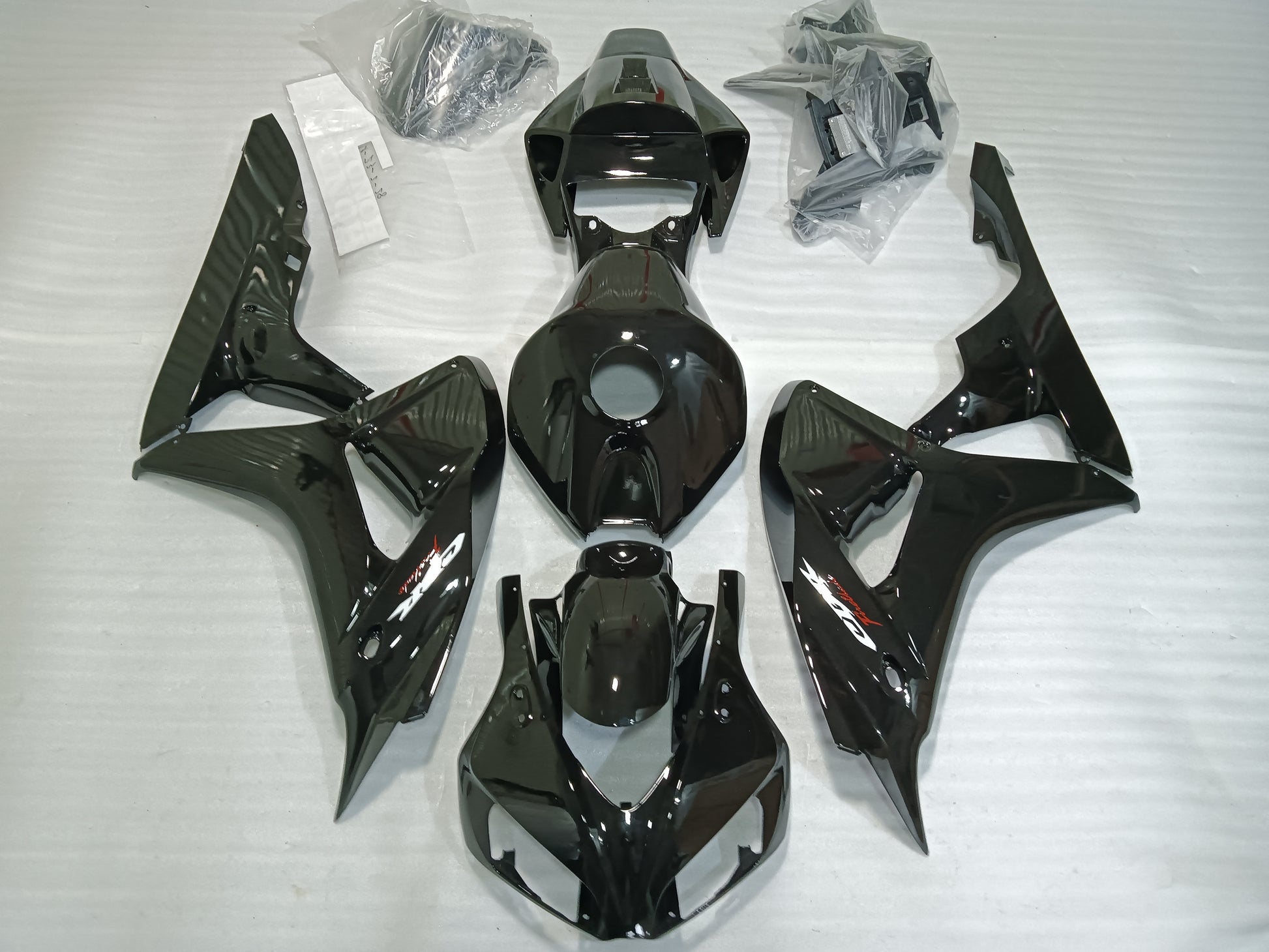 Set of black motorcycle fairings including panels, bolts, windscreen, and heat shield laid out on a white background.