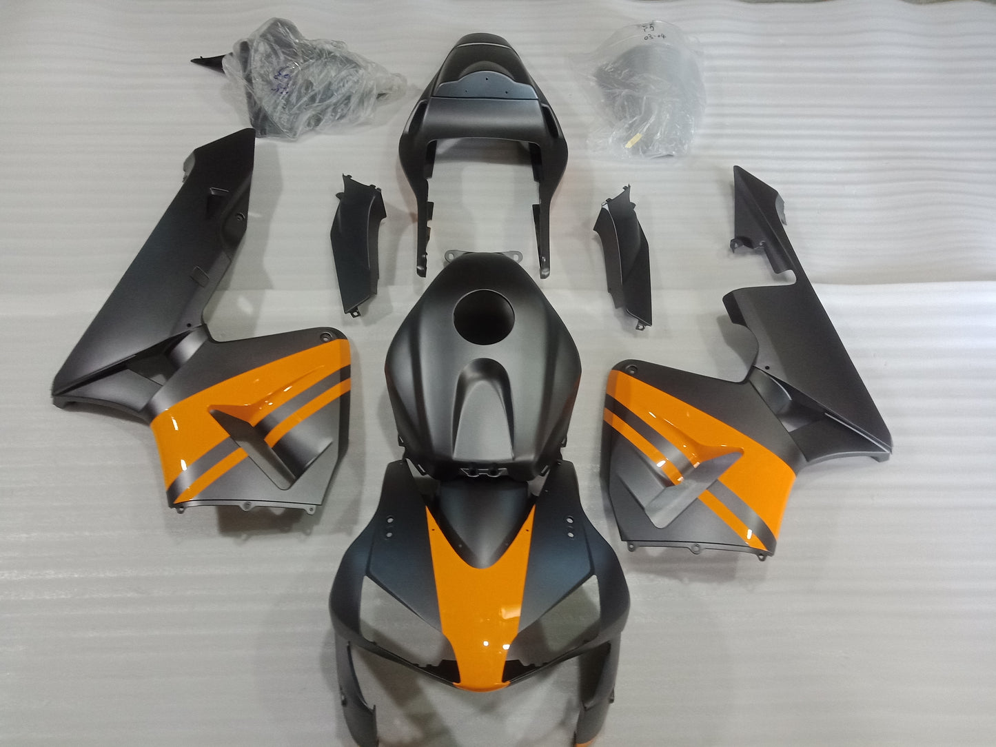 Set of motorcycle fairings in matte black with yellow accents, including various panels and accessories, displayed on a white background.