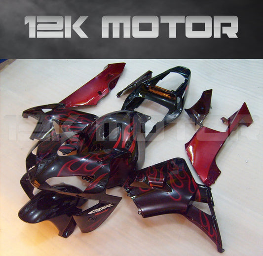 Aftermarket fairing kit for HONDA CBR600RR motorcycle, featuring black panels with red flame designs, laid out on a table.