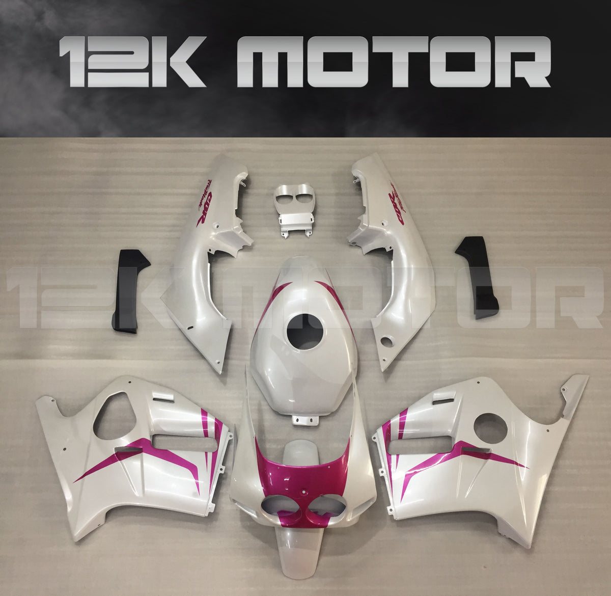Aftermarket fairing set for HONDA CBR250RR MC19 in white with pink accents, displayed on a table.
